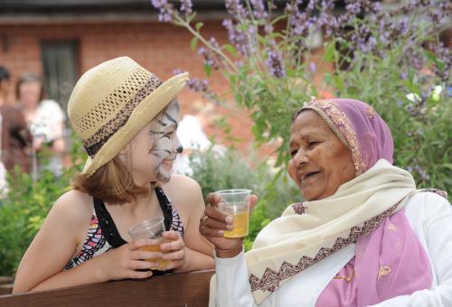 Girl with facepaint and elderly lady enjoying a drink together